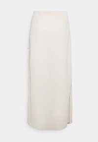 Dlouhá sukni v krémové barvě se rovnou siluetou, bočním rozparkem a jemnými knoflíkovými detaily podél levého švu v hladkém textilním provedení.