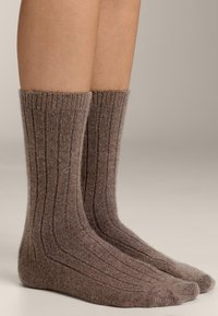 Calze di lana marroni a coste con una texture morbida, dotate di un bordo risvoltato e di una punta rinforzata per la durata. Il design enfatizza calore e comfort.