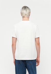 White cotton T-shirt with short sleeves, a crew neckline, and a relaxed fit, displayed from the back against a plain background.