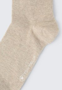 Beige Baumwollsocke mit einer weichen Textur, geripptem Design und einem dezenten Logo auf der Seite. Runde Zehen und verstärkte Ferse.