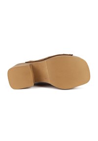Tan rubber sole with textured grip, featuring a sturdy block heel. The footbed includes decorative studs along the upper edge.