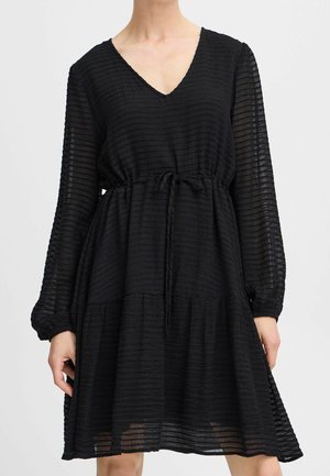 Sort langærmet kjole med V-hals og teksturerede horisontale striber, indsnævret talje med et knyttet bælte og en udvidet nederdel, der slutter over knæene.