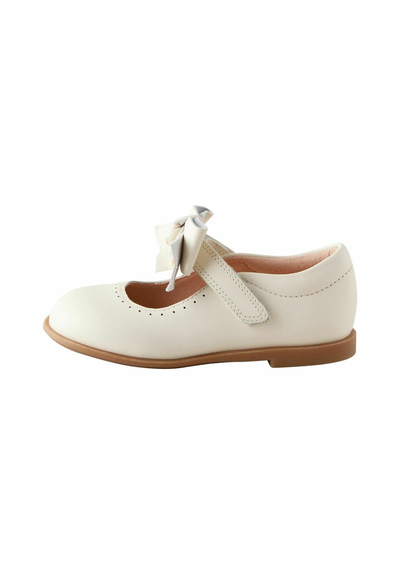 Chaussure Mary Jane en cuir couleur crème avec un nœud sur la bride et petits détails perforés autour de la zone des orteils, semelle plate marron.