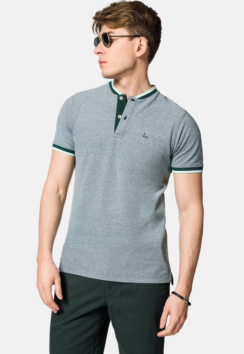Szara koszulka polo z zielonym kołnierzykiem i mankietami, z placketem na dwa guziki oraz małym logo na piersi. Gładka tekstura materiału.