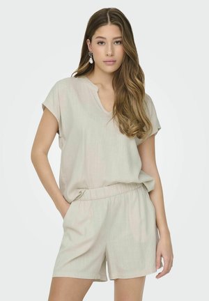 Lichtbeige outfit met een T-shirt met korte mouwen en een V-hals, gecombineerd met shorts met elastische taille. Zachte, textuurstof met een ontspannen pasvorm.