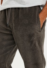 Fleece jogger broek in donkerbruin, met een zachte textuur, een elastische tailleband met verstelbare trekkoorden en zijzakken.