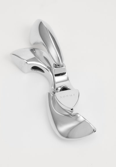 Srebrna metalna sponka za lase s sleek, ukrivljenim dizajnom. Ima poliran zaključek, vgraviran logotip in varen sponka za držanje las.