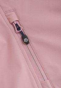 Ljusrosa tyg med en slät yta har en dragkedjeficka, prydd med en mörkblå dragkedja med en svart dragflik.