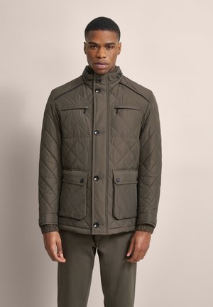 Quilted olive green jacket with a high collar, contrasting black buttons, and two front pockets. Features ribbed cuffs and a tailored fit.