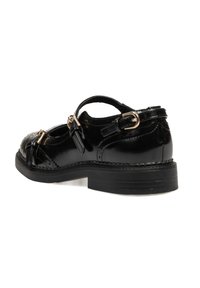 Zapato de charol negro con punta redondeada, detalles de hebilla y suela plana. Presenta acentos perforados y una correa sobre el empeine.