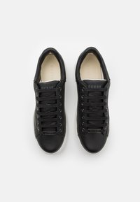 Svarta lädersneakers med en slät yta, vit gummisula, rund tå och snörningsdesign. Har en liten "GUESS"-logga på sidan.