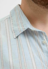 Camisa de color azul claro con cuello, que presenta rayas verticales blancas y marrones, con una tapeta de botones y una tela suave y texturizada.