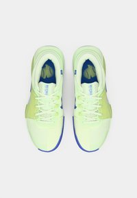 Ζευγάρι από αθλητικά παπούτσια Nike σε νεον πράσινο και μπλε χρώμα με κορδόνια, σε θέα από πάνω σε λευκό φόντο.