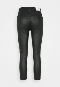 Jeans skinny pretos feitos de um tecido elástico, com um cós com uma etiqueta branca e dois bolsos traseiros com um design subtil.