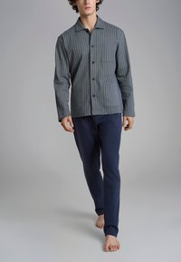 Camicia a righe grigia e blu con taschino sul petto, abbinata a pantaloni blu navy. Tessuto morbido e vestibilità rilassata, progettata per il comfort.