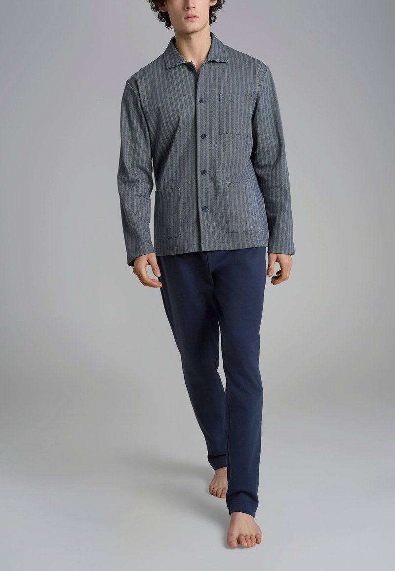 Camicia a righe grigia e blu con taschino sul petto, abbinata a pantaloni blu navy. Tessuto morbido e vestibilità rilassata, progettata per il comfort.