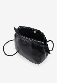 Bolso de cuero negro con una textura suave, cierre de cordón y una correa larga. El interior cuenta con un pequeño bolsillo y un broche en tono dorado.