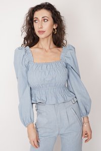 Jasnoniebieska bluzka z denimu z bufkami, marszczoną talią i kwadratowym dekoltem. Posiada marszczoną fakturę i skróconą długość.