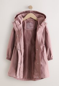 Imperméable à capuche mauve clair avec poignets élastiques, boutons-pression et fermeture éclair, suspendu ouvert sur un cintre en bois sur fond uni.