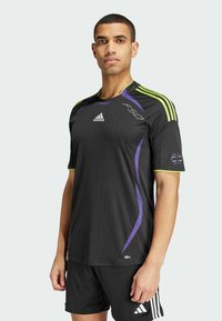 Zwart atletisch shirt met verticale strepen, paarse en groene accenten, korte mouwen, Adidas-logo op de borst en F50-branding aan de zijkant.