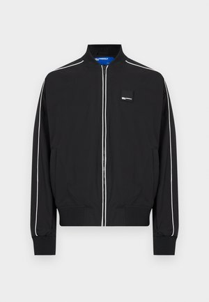 Μαύρο μπουφάν τύπου bomber με φερμουάρ, λευκά περιθώρια στα μανίκια και στο μπροστινό μέρος, ριμπ μανσέτες και γιακά, και μικρό λογότυπο στον θώρακα.