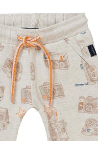 Beige kinderbroek met cameraprints, oranje trekkoord, geribde tailleband en steraccenten. Gemaakt van zacht, textuurmateriaal.