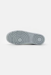 Light gray sneaker sole featuring concentric circular patterns, smooth texture, and embossed branding. No visible wear or damage.