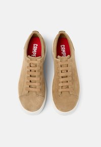 Sneakers in suede beige con sei lacci beige, una suola in gomma bianca e una soletta rossa con il logo "CAMPER" in bianco.