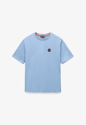 Vaaleansininen puuvillapaidat, jossa on lyhyet hihat, pyöreä kaula-aukko ja pyöreä musta ja oranssi logo vasemmassa rinnassa.