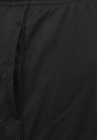 Zwarte stoffen shorts met een soepele textuur, voorzien van een zijzak en een elastische band. Het materiaal lijkt lichtgewicht en duurzaam.