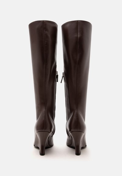 Paire de bottes hautes en cuir marron foncé avec fermetures éclair latérales et talons moyens vue de dos sur fond blanc.