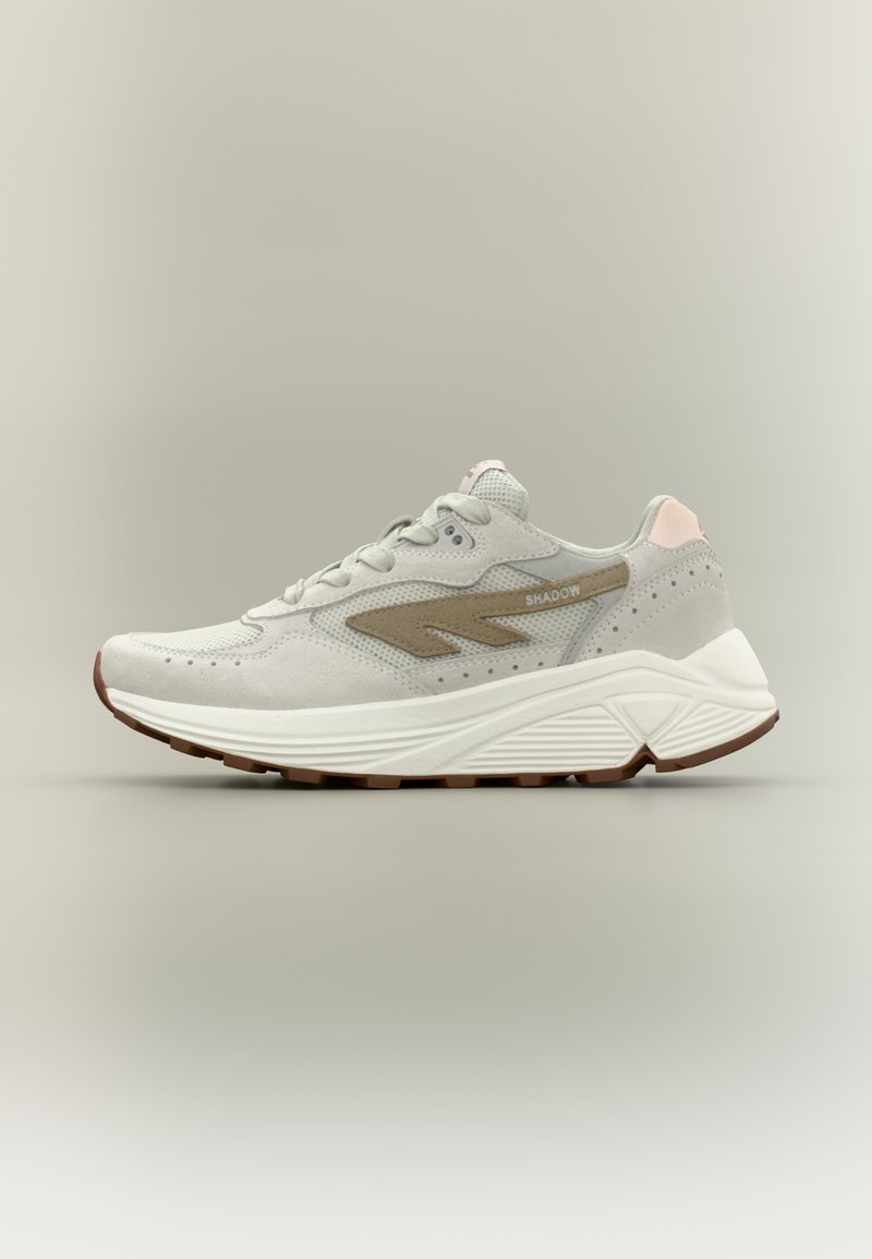 Grijze sportschoen met een gestructureerde bovenkant, beige accenten en een witte middenzool. Heeft een afgeronde neus en een rubberen buitenzool met patroon.