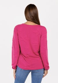 Langärmliges Oberteil in leuchtendem Pink, mit einem strukturierten Blumenmuster. Lockerer Schnitt mit rundem Halsausschnitt und gerafften Ärmeln.