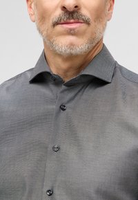 Grijze, knoopsluiting overhemd van een gestructureerde stof. Beschikt over een klassieke kraag, zes knopen en contrasterende details aan de binnenkraag.