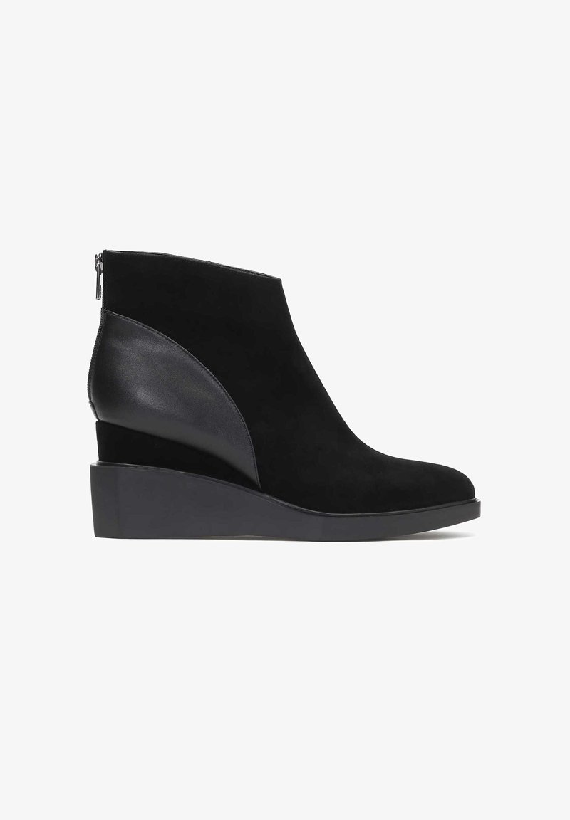 Bottine noire à talon compensé avec panneaux latéraux en suède et cuir, bout rond et fermeture éclair au dos.