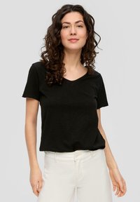 Zwarte v-hals t-shirt, korte mouwen, zachte stof, comfortabele pasvorm. Gecombineerd met witte broek met hoge taille, minimalistisch ontwerp zonder zichtbare patronen.