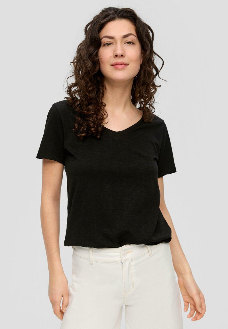 Zwarte v-hals t-shirt, korte mouwen, zachte stof, comfortabele pasvorm. Gecombineerd met witte broek met hoge taille, minimalistisch ontwerp zonder zichtbare patronen.