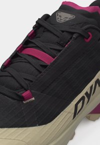 Μαύρο και ματζέντα παπούτσι για τρέξιμο σε μονοπάτι με υφασμένο μπεζ σόλα, μαύρα κορδόνια και λογότυπο στη γλώσσα και στο πλευρικό μέρος.