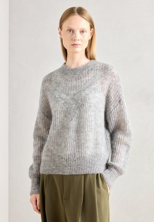Light grey knitted sweater with a ribbed texture, round neckline, and slightly sheer sleeves. Worn over olive green trousers.