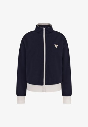Marineblauwe ritjas met hoge kraag en witte accenten aan de zoom en manchetten. Bevat een klein driehoekig logo op de linkerborst. Zacht materiaal.