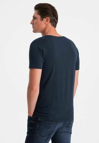 Námořnická modrá tričko s krátkým rukávem a kulatým výstřihem, vyrobené z měkké tkaniny. Zadní strana má hladký, jednoduchý design bez vzorů.
