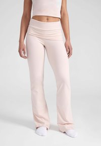 Lichtroze flared leggings met een brede omslag tailleband, gemaakt van een rekbaar stof, met een gladde textuur en een aansluitende pasvorm.