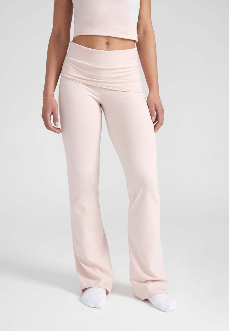 Lichtroze flared leggings met een brede omslag tailleband, gemaakt van een rekbaar stof, met een gladde textuur en een aansluitende pasvorm.