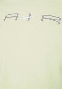 Light green cotton t-shirt featuring a printed graphic with the text "AIR" in grey and a white Nike swoosh logo. Smooth fabric texture.