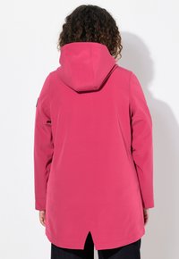 Rosa huva jacka med en avslappnad passform, har splittrad nederkant, sidofickor och en slät, något glansig tygstruktur.