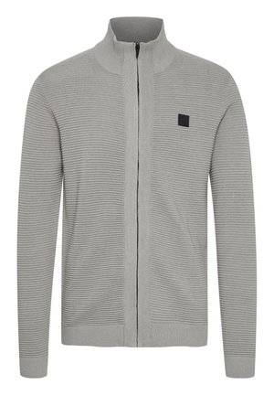 Grå zip-up genser med ribbet tekstur, høy krage og svart akcentmerke på brystet. Slim fit med lange ermer og elastiske mansjetter.