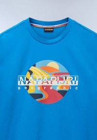 Modré bavlněné tričko s kruhovým grafickým designem s abstractními tvary v oranžové, žluté a modré barvě. Logo "NAPAPIURI" ve středu.