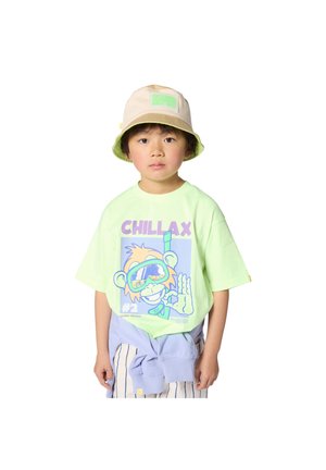 Dziecko w beżowym kapeluszu typu bucket i pastelowozielonej koszulce z rysunkowym małpą i napisem "CHILLAX", lekka kurtka zawiązana w talii.