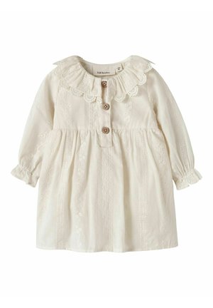 Robe bébé crème à manches longues avec col volanté en dentelle, trois boutons en bois sur le devant et motifs floraux verticaux brodés.