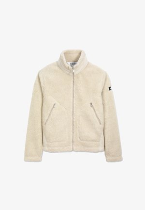 Veste en polaire couleur crème avec un col montant, deux poches avant zippées et une étiquette de marque sur la manche gauche. Texture douce et design chaud.